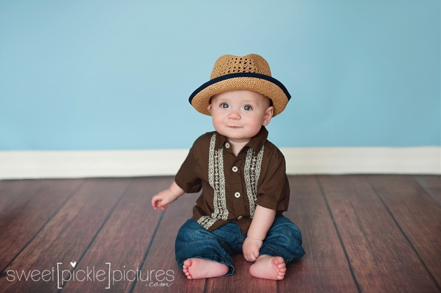 6 month baby sitting up with straw hat studio